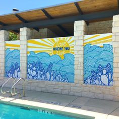 a swimming pool next to a building with murals on the wall and in the water