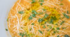 a bowl of soup with cheese and parmesan on top, ready to be eaten