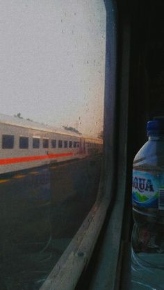 a bottle of water sitting next to a train window