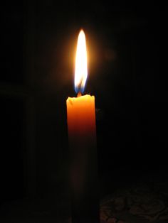 a lit candle in the dark with its light shining on it's side,