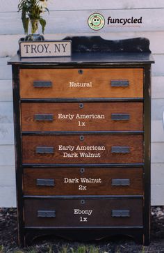 an old dresser with many drawers and labels on it's sides, in front of a white house