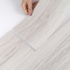 a person is placing something on top of a white wall with wood planks in the background