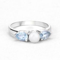 Pearl Ring, Dainty White Pearl and Blue Topaz Silver Ring for Women, June Birthstone Ring, Stackable Ring, Gift for Her, Gifts for MomFlaunt yourself with this beautiful white pearl ring for women. The natural white pearl and blue topaz gemstones have a combined weight of 1.56 carats and are set in .925 sterling silver with rhodium plating. The rainbow white and blue mix hues of this gemstone ring adds a pop of color to any look!  The understated design and vibrant stones makes this white pearl Three-stone Aquamarine Jewelry For Gift, Three Stone Aquamarine Jewelry As A Gift, Three Stone Aquamarine Jewelry For Gift, Blue Topaz Three Stone Promise Ring, Blue Topaz Birthstone Crystal Ring, Multi-stone Blue Topaz Rings For Promise, White Blue Topaz Jewelry For Promise Ring, Blue Topaz Multi-stone Promise Ring, Aquamarine Rings With Gemstone Accents For Promise