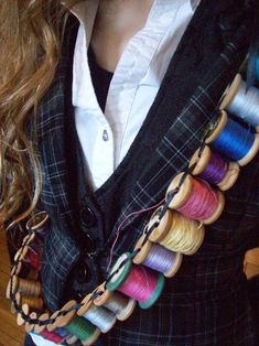 a woman wearing a vest with multiple spools of thread on it's back