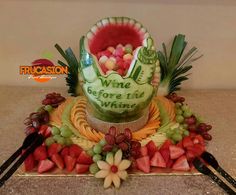 a cake made to look like a watermelon with grapes, strawberries and pineapples