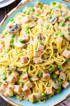 pasta with ham, peas and mushrooms on a blue plate