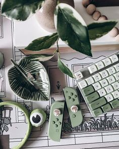 a computer keyboard sitting on top of a desk next to a plant and other items