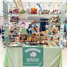 a woman standing in front of a table with stuffed animals and toys on it's sides