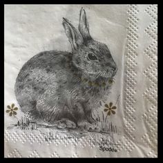 a napkin with a drawing of a rabbit on it's side and daisies in the background