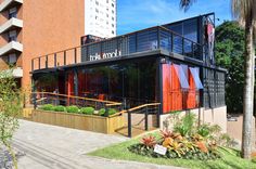 the building has red and black panels on it's sides, along with palm trees