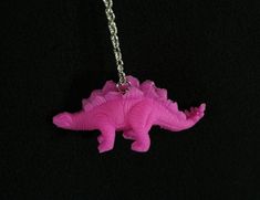 "This cute and colorful necklace features a bright pink handmade dinosaur charm on a silver chain, and would be a perfect addition to your Lost Lands fit, Halloween costume, or just a fun twist on any outfit.  The lightweight, flexible charms are made by hand from upcycled plastic dinosaur toys. The chain is 23\" long." Pikachu Beads, Rave Necklace, Plastic Dinosaur, Feather Hair Comb, Handmade Dinosaur, Rave Jewelry, Kandi Necklace, Streetwear Jewelry, Lost Lands