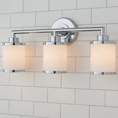 three light bathroom fixture in chrome finish with frosted glass shades on white brick wall