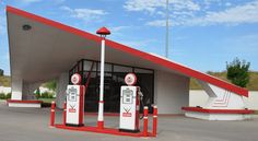 an empty gas station with two red and white pumps on the ground next to each other