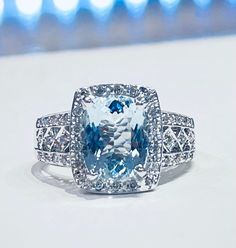 a fancy blue and white diamond ring with diamonds on the sides, set in 18k white gold