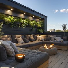 an outdoor living area with couches, fire pit and potted plants on the roof