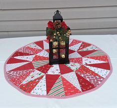 a table topped with a red and white quilted place mat covered in christmas decorations