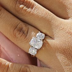 a woman's hand with a three stone diamond ring on top of her finger