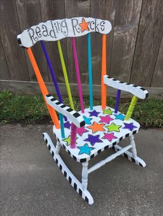 a colorful wooden rocking chair with reading rocks written on the back and stars painted on it