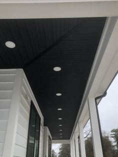 the front porch is lined with windows and white walls, along with black ceiling tiles