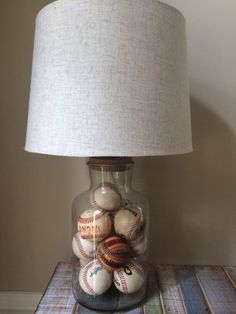 a glass jar with baseballs in it sitting on a table next to a lamp