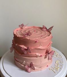 a three layer cake with pink frosting and butterflies