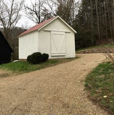 a white shed sitting on top of a gravel road