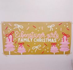 a christmas sign hanging from the side of a wall with pink frosting on it