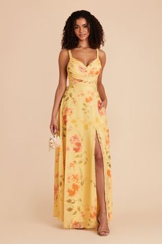 a woman wearing a yellow floral print dress with thigh high slits and an open back