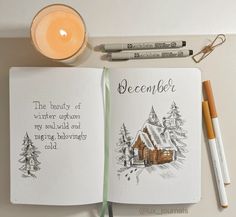 an open book with writing on it next to a candle and some pens, pencils and markers