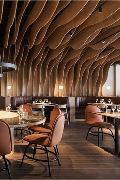 a restaurant with tables and chairs in front of large windows that have wavy wood panels on the ceiling