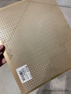 a person is holding up a piece of metal sheet that has been cut into squares