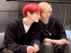 two young men sitting next to each other in front of a television screen with red hair