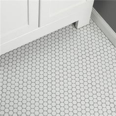 a white bathroom with hexagonal tiles on the floor