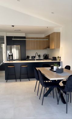 an open kitchen and dining room area with black chairs, counter tops, and white tile flooring