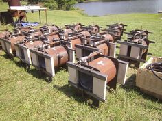 many old televisions are sitting in the grass near some water and trees on a sunny day