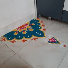 a blue and yellow rug sitting on top of a white floor next to a toilet