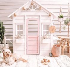 a dog is laying on the floor in front of a doll house and potted plants