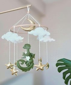 a green dragon mobile hanging from the ceiling next to a potted plant and moon