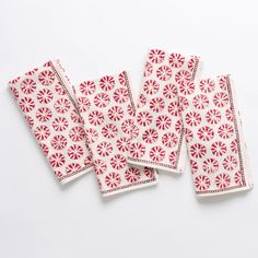 four red and white napkins on a white surface with small circles in the middle