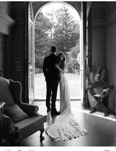 a bride and groom standing in front of an open door