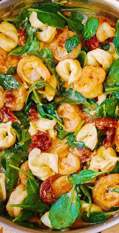 spinach and shrimp with sun dried tomatoes in a pan on a wooden table top