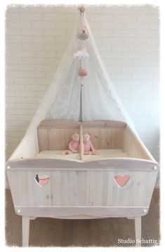 a baby crib with a pink teddy bear in it and a white net hanging from the top