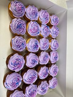 a box filled with purple frosted cupcakes