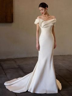 a woman in a white wedding dress standing on a tile floor with her hands behind her back