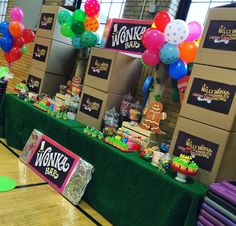 a table topped with lots of boxes filled with cakes and candy next to balloons in the shape of gingerbreads