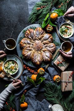 several people are eating food from plates on a table with oranges and evergreen leaves