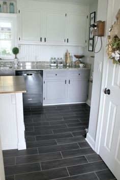 a kitchen with white cabinets and black tile flooring