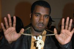 a man in a leather jacket holding his hands up and wearing a chain around his neck