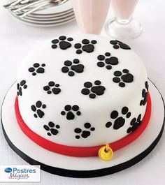 a cake decorated with black and white dog paw prints on a plate next to silverware