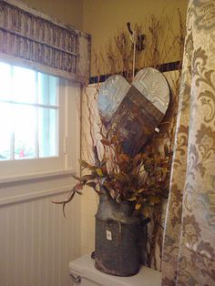 a bathroom with a toilet, window and curtain in the corner next to it is a potted plant that has been placed on top of an old metal bucket